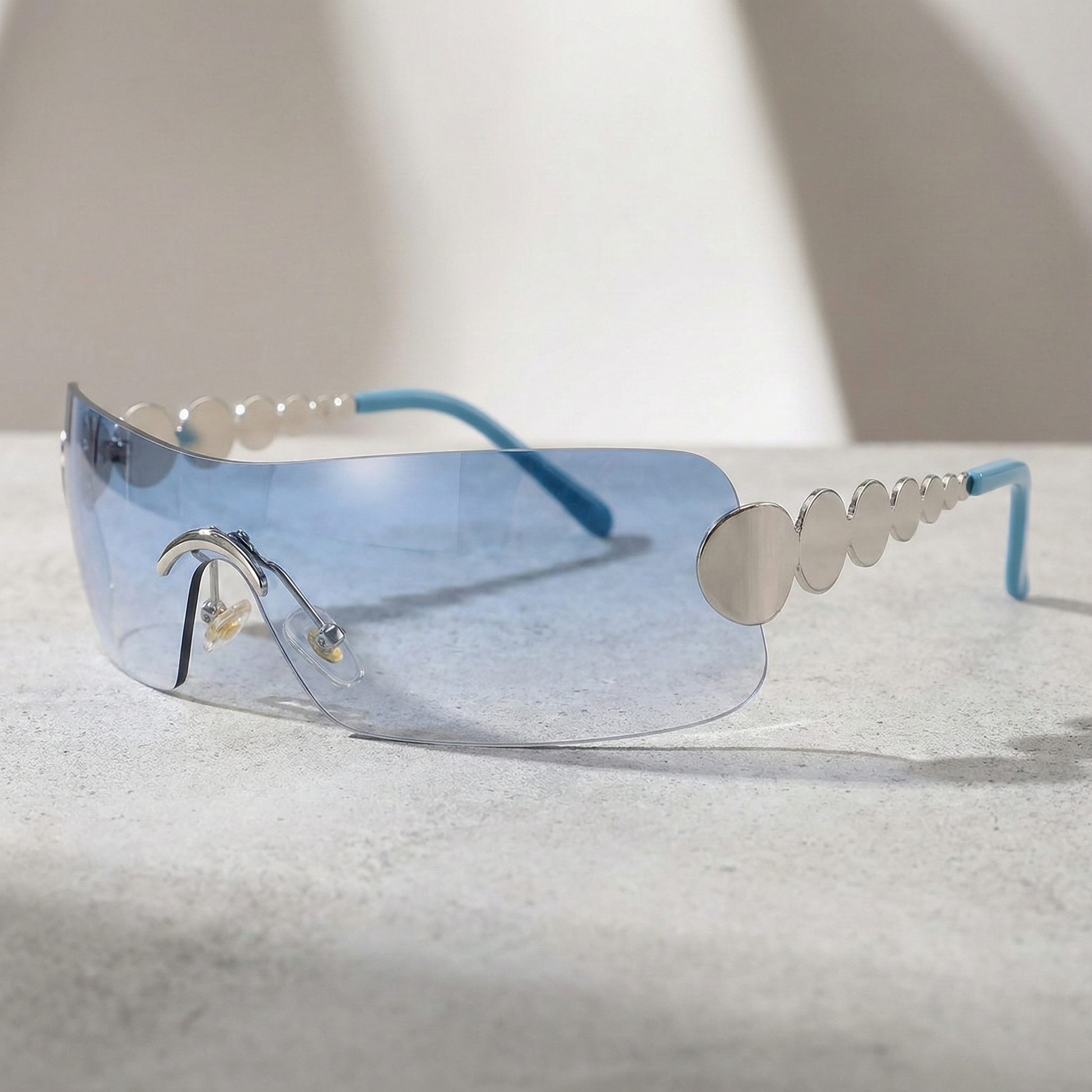 Sunglasses with blue lenses and silver frame on a light surface