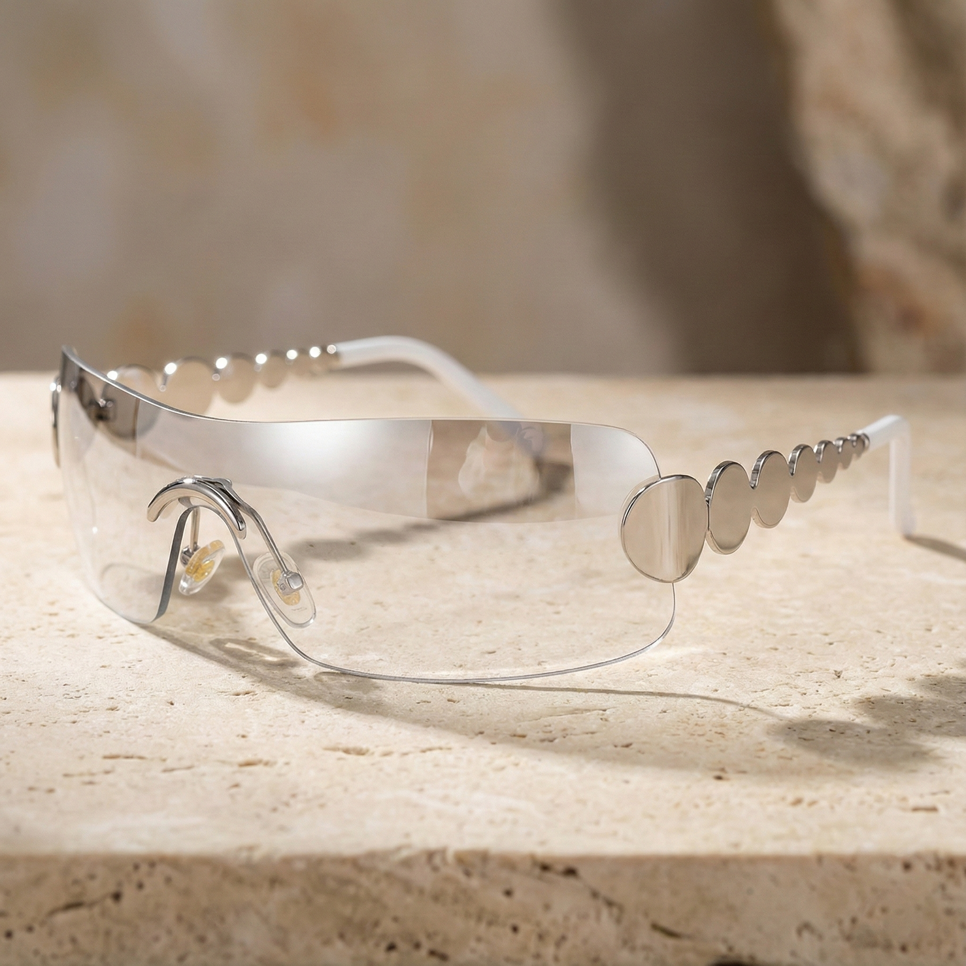 Clear safety goggles with metallic accents on a stone surface