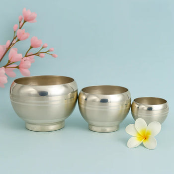 Three metallic bowls of different sizes on a light blue background with flowers.