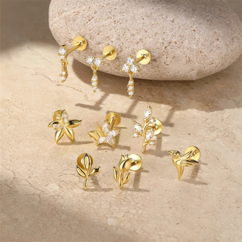 Gold earrings with floral designs on a stone surface