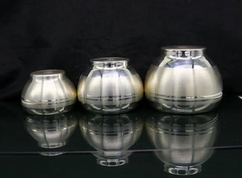 Three metallic silver objects on a reflective black surface with a dark background